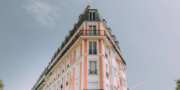 blue sky and a beautiful unique building. The building is coral with white trim