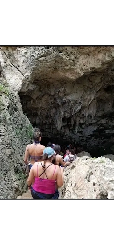Group entering a rocky cave with natural formations.