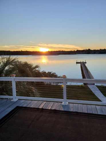 Sunset over a calm lake with a wooden dock and railing in the foreground.