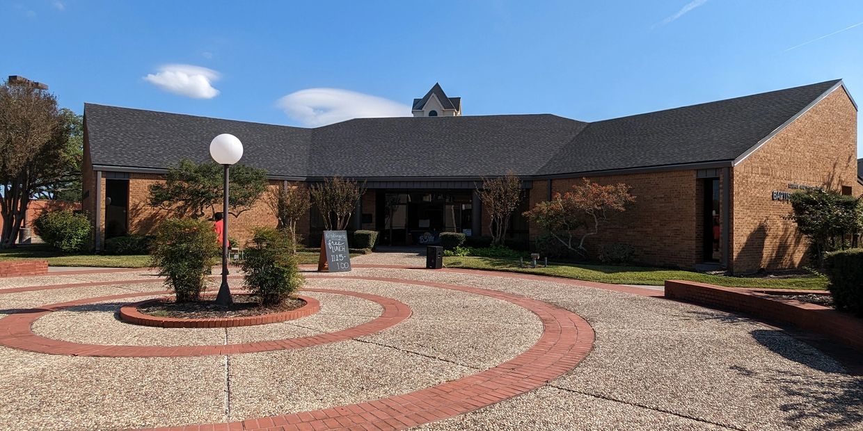 Brick building with circular paved courtyard and lamppost.