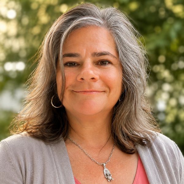 Smiling woman with gray hair outdoors.