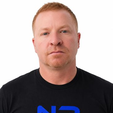 Portrait of a serious man with short red hair and a black t-shirt.