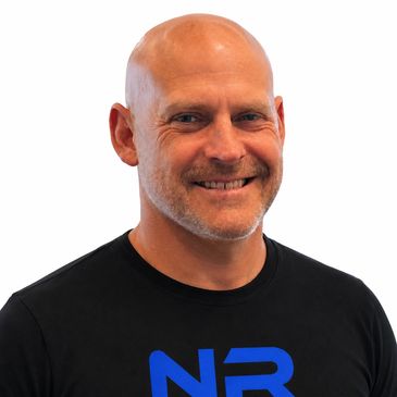 Smiling bald man in black t-shirt with blue letters.