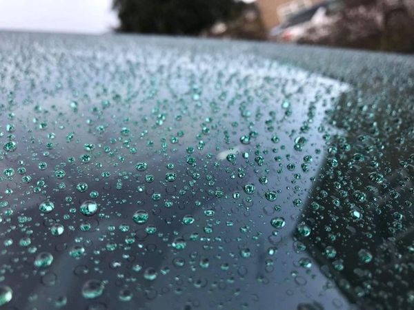 Close-up of water droplets on a smooth surface, reflecting light.