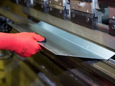 Worker using a machine to bend a metal sheet.