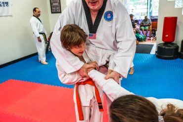 martial arts teacher helping students with orange belt