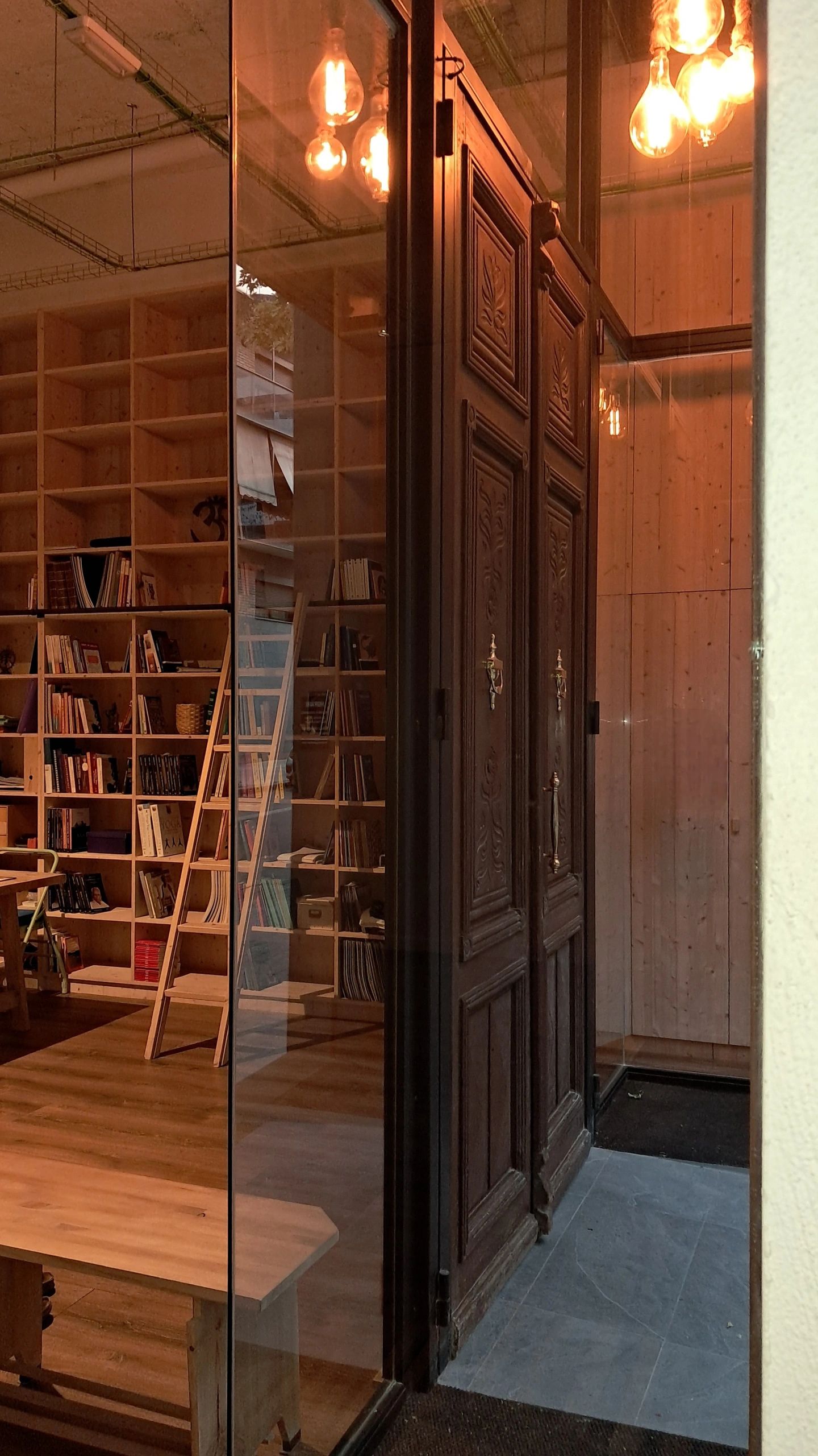Cozy library room with wooden shelves, ladder, and carved wooden doors.