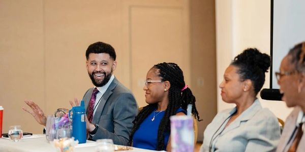 A diverse group engaged in a lively panel discussion indoors.