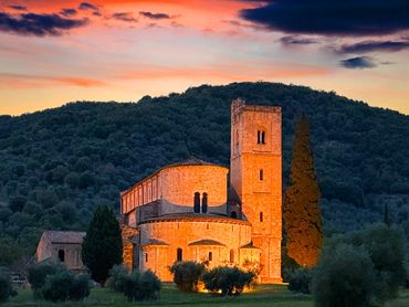 Historic stone church illuminated at sunset in a serene countryside.