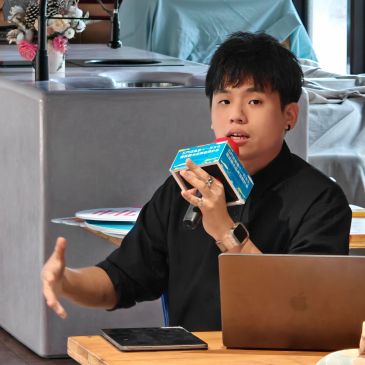 Young man speaking into microphone during a presentation.