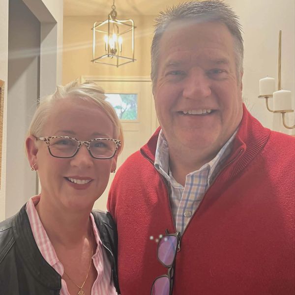 Smiling middle-aged couple indoors, warm lighting.