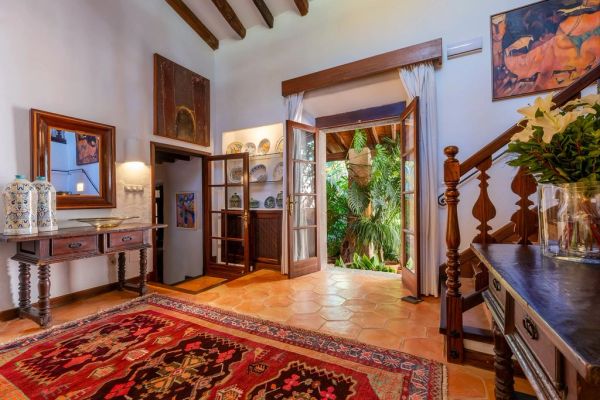 Rustic home entrance with wooden doors and vibrant rug.