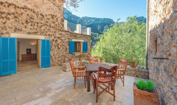 Cozy outdoor patio with wooden chairs and blue shutters.