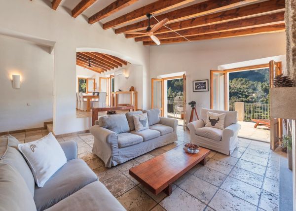 Bright living room with wooden beams and mountain view.