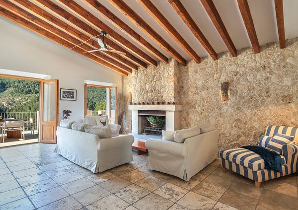 Cozy living room with stone wall and wooden ceiling beams.