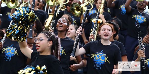 A lively youth band performs passionately with instruments and cheerleading pom-poms.