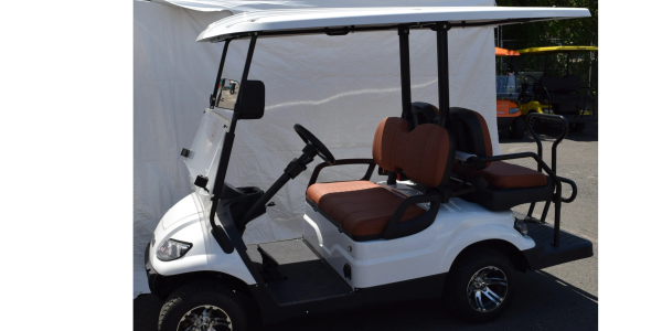 White 4-seat golf cart with brown seats parked outdoors.
