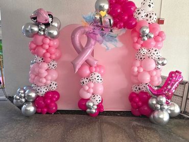 Pink-themed balloon decoration with breast cancer awareness ribbon and number 1.