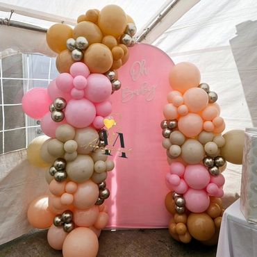Colorful balloon columns with a pink backdrop for a baby celebration.
