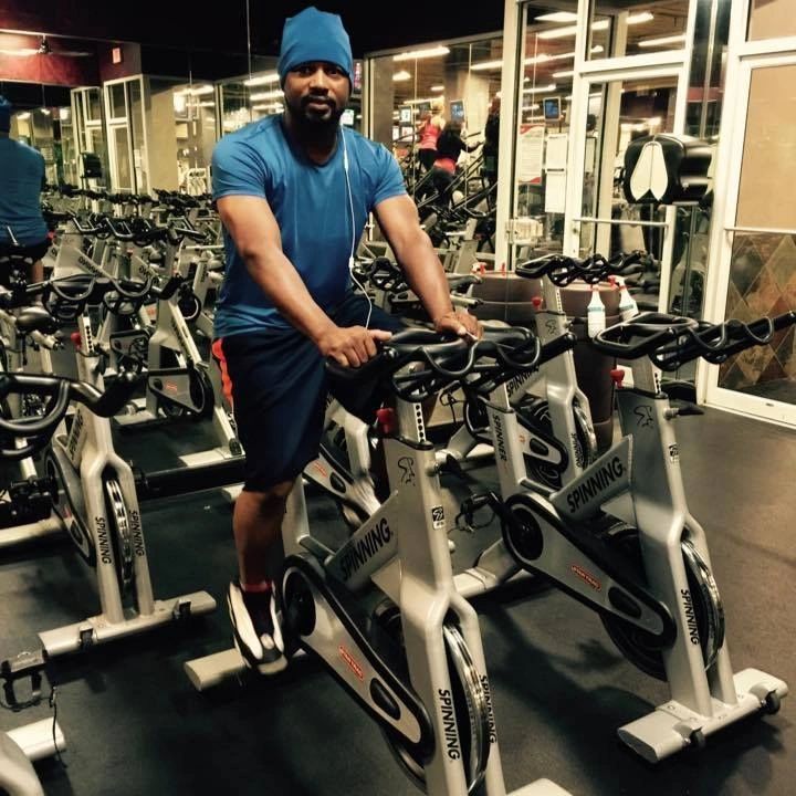 Man in blue outfit on a spinning bike at the gym.