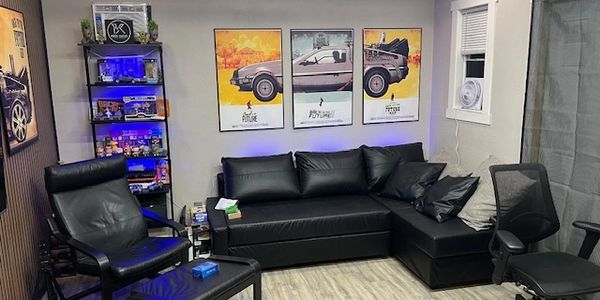 Modern living room with black leather furniture and Back to the Future posters.