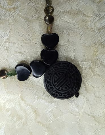 Black heart-shaped and round beads on lace fabric.