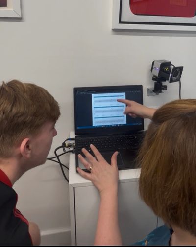 Two people discuss data displayed on a laptop screen in a room.