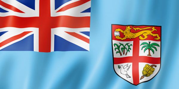 Flag of Fiji with a light blue background and a detailed coat of arms.