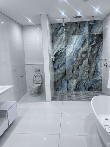 Modern bathroom with white tiles and a striking marble shower wall.