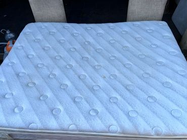 A white mattress with circular patterns and some stains.