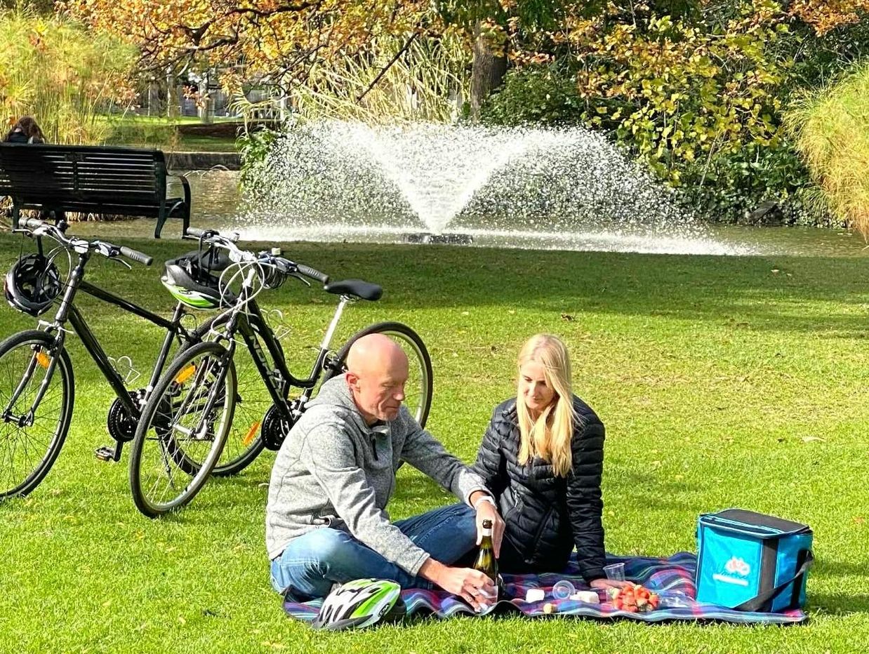 Couple picnicking near a fountain in a park.