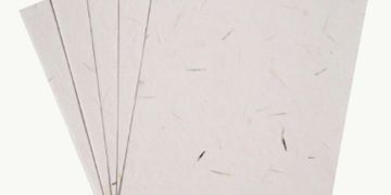 A stack of six off-white textured paper sheets with natural fibers.