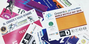 A collection of colorful marathon and cycling event bibs from various races.