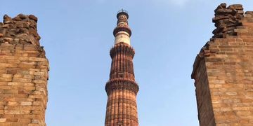 The Qutub Minar tower with a crowd of visitors around it.