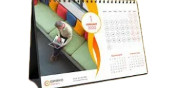 A desk calendar open to January 2022 with a person reading on a green couch.
