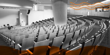 Empty modern auditorium with curved seating arrangement and a podium on stage.