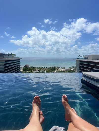 Relaxing feet in an infinity pool overlooking the ocean and sky.