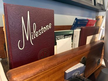 A vintage 1957 Milestone book among other books on a wooden shelf.