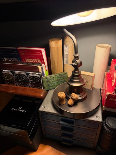 Jury + Field Watch Desk with vintage desk lamp, metal cabinet, watch boxes, and wooden radio cabinet