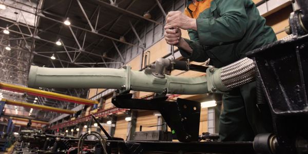 Worker assembling a large mechanical part in a factory.
