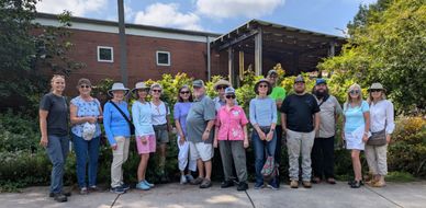 group of people standing in front of a brick building and garden
