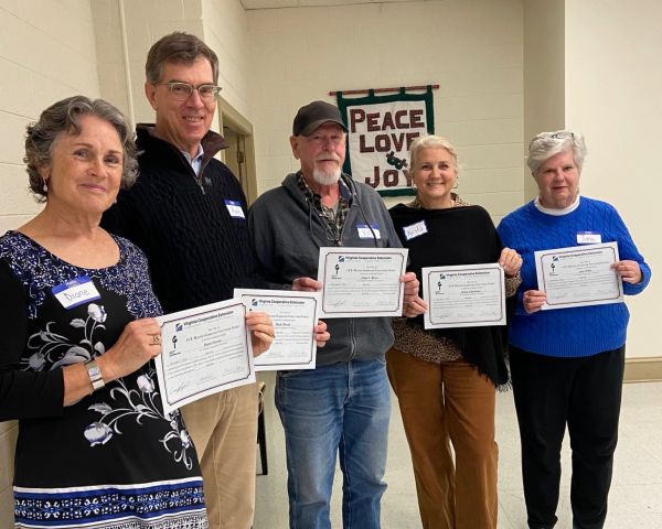 group of people holding up certificates to demonstrate completion of master gardener training