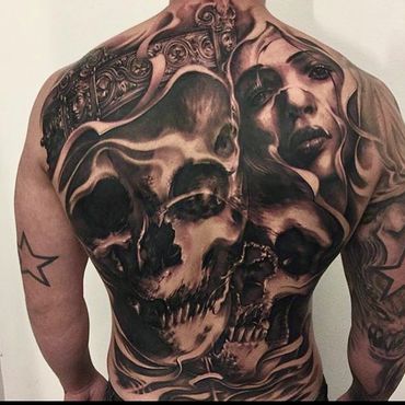 Intricate black and grey back tattoo featuring skulls and a woman's face.