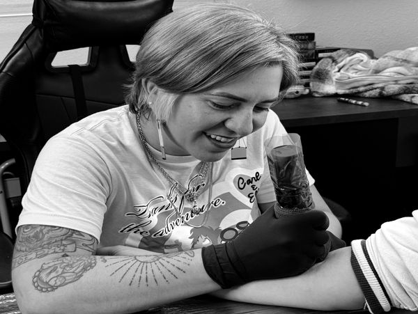 Tattoo artist focused on inking a client's arm in a cozy studio.