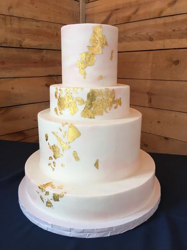 4 tiered wedding cake with light pink marbling and gold leaf cascading across front