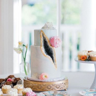 Two tiered cake with grey geode cut out of the front and vanilla cupcakes with flowers