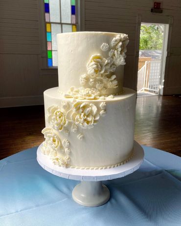 2 tiered wedding cake with white buttercream flowers cascading across front