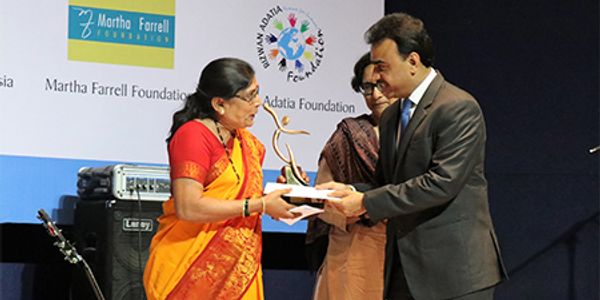 Woman receiving an award from a man in a suit.