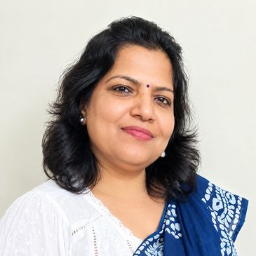 Smiling woman wearing a white blouse and blue patterned shawl.