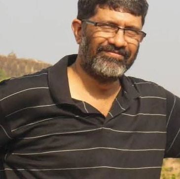 Man with glasses and beard, wearing a black striped shirt.